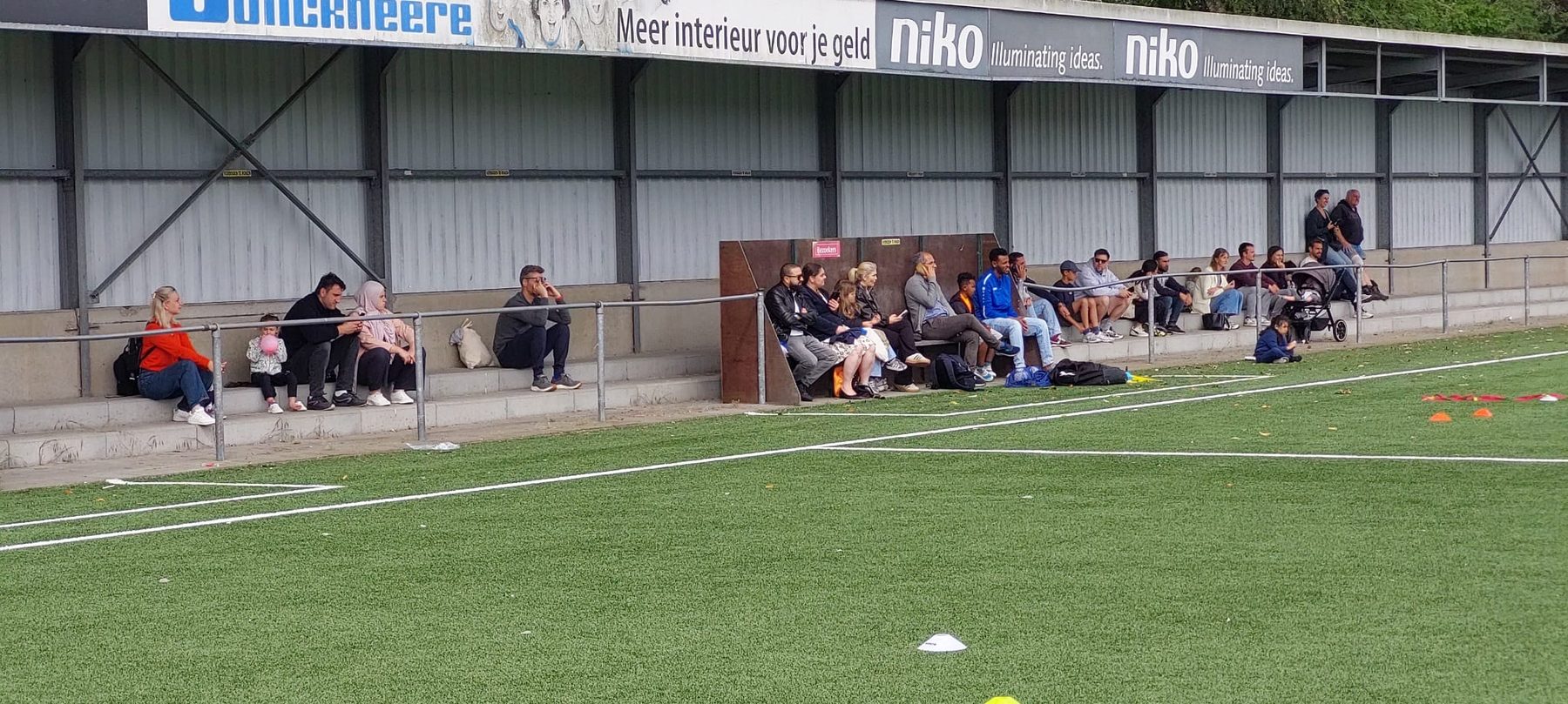 Supporters en ouders op de tribune langs het hoofdveld